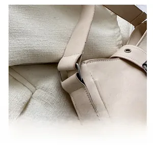 Detail view of beige leather shoulder bag showing silver metal buckles and neat stitching
