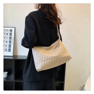 Detail of beige quilted tote bag with knot strap and elegant diamond lattice texture