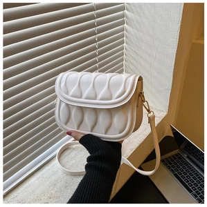 Detail of white saddle bag showing unique vertical wave pattern quilting and gold buckle