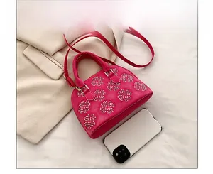 Détail du sac en daim rose avec motifs floraux cloutés et smartphone pour comparer la taille