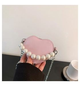 Vue détaillée du mini sac rose en forme de cœur avec anse perlée et chaîne argentée