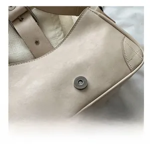 Detail of magnetic snap closure and adjustable buckle strap on off-white square bag