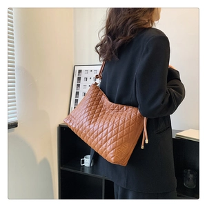Detail of caramel brown quilted bucket bag showing diamond stitching and metal rings
