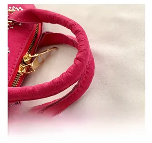 Gros plan sur le sac en daim rose rouge avec détails en strass et poignée confortable