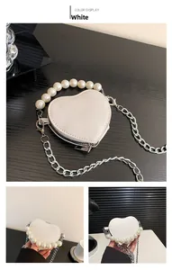 Détails d'un mini sac blanc en forme de cœur avec poignée en perles et chaîne argentée