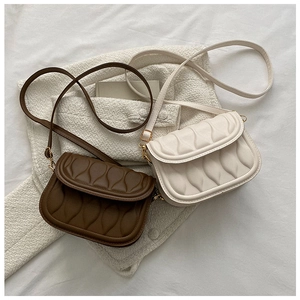 Detail view of wave quilted shoulder bags in dark coffee and cream white colors