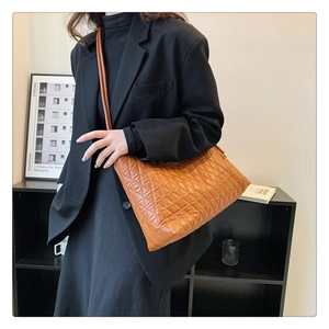 Detail of a brown quilted bucket bag with a classic diamond pattern and slender shoulder strap