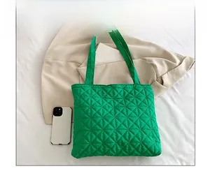 Detail of bright green quilted nylon tote bag with rhombus stitching on beige clothing