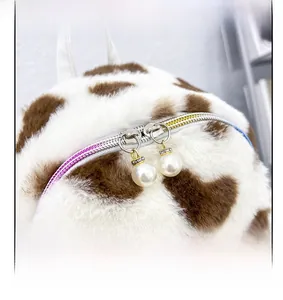 Détail d'un sac à dos en peluche avec doubles fermetures éclair et pendentifs en perles