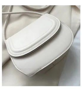 Close-up of white half-moon saddle bag with fine PU leather texture and neat stitching