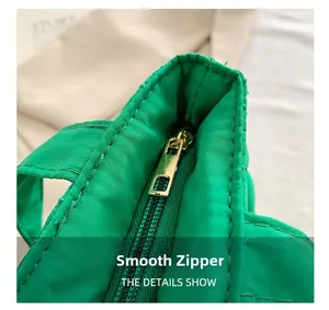 Detailed close-up of a high-quality smooth gold metal zipper on a green tote bag