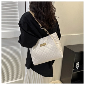 Detail of white quilted tote bag with gold chain strap and FASHION logo on female model