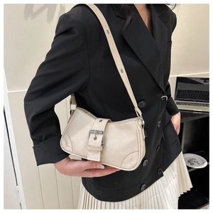 Detail of cream matte shoulder bag featuring metal buckle and decorative stitching