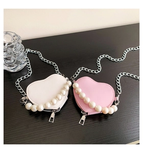 Détail de mini sacs en forme de cœur avec perles et chaînes en blanc et rose poudré