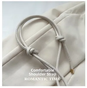 Detail of soft cream leather tubular shoulder strap with knot and gold metal end caps
