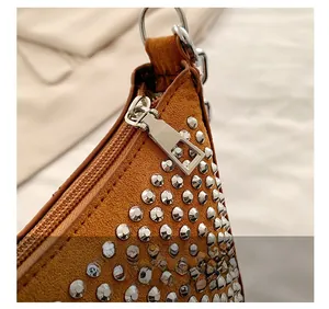 Close-up of brown suede shoulder bag with metallic silver rivets and zipper detail