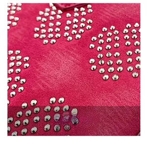 Détail macro du sac coquillage en daim rose fuchsia avec motifs de rivets fleuris argentés