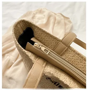 Detail of smooth metal zipper closure on a large capacity woven straw tote bag