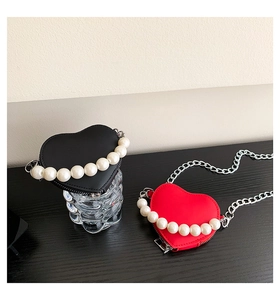 Détail de sacs en forme de cœur rouges et noirs avec poignées en perles et chaîne argent