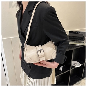 Detail of cream leather square bag showing adjustable metal buckle and reinforced stitching