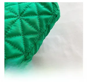 Close-up of quilted emerald green shoulder bag showing fine diamond stitching texture
