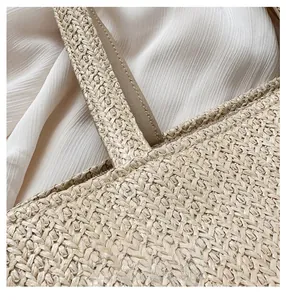 Close-up of reinforced stitching on beige straw tote bag with lychee grain leather trim
