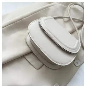 Detail view of cream saddle bag featuring smooth leather texture and refined stitching