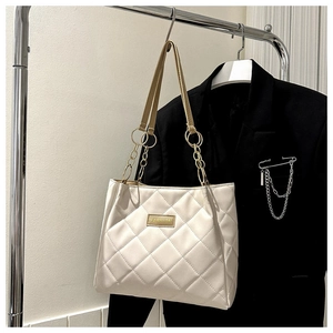 Detail of off-white quilted shoulder bag with gold metal fashion lettering and chain strap