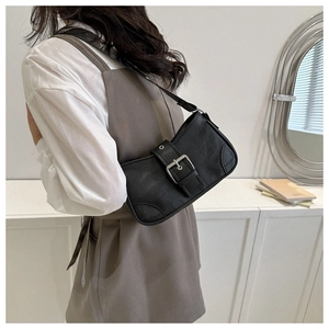 Detail of a black faux leather underarm bag featuring a silver square metal buckle