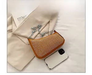 Size comparison of yellow studded crossbody bag with a white smartphone on textured fabric