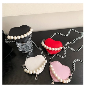 Détail de mini sacs en forme de cœur en quatre couleurs avec poignées en perles et chaîne