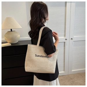 Detail of a large woven tote bag with Sunshine Girl print worn by a woman in a suit