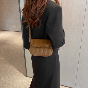 Vintage brown quilted shoulder bag with gold hardware worn by model in a black blazer