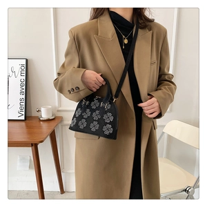 Détail du sac coquillage noir avec motifs floraux en perles blanches et poignées