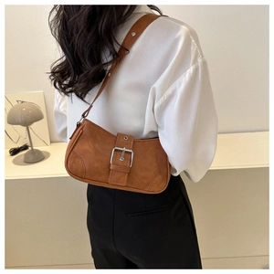 Detail view of brown faux suede shoulder bag featuring a large silver buckle and strap