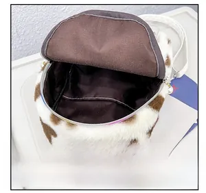 Détail du sac en peluche à motif vache avec doublure marron et zip orné de perles