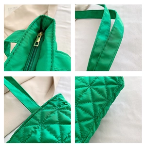 Detail view of green quilted tote bag showing sturdy metal zipper and reinforced stitching