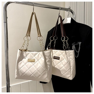 Detail of quilted tote bags with fashion tags and elegant metal chain leather straps