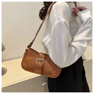 Macro view of vintage brown frosted leather underarm bag with silver buckle and sleek strap