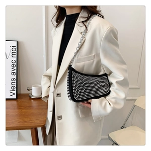 Model wearing a black studded half-moon shoulder bag with bold silver metal chain strap
