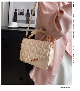 Détail du sac beige matelassé avec finitions dorées et poignée haute froncée