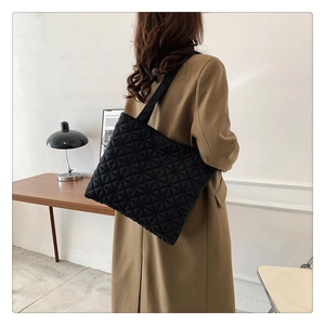 Close-up of black quilted tote bag with diamond stitching showing texture and wide strap