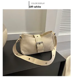 Detail view of off-white minimalist baguette bag with metallic buckle and eyelet strap