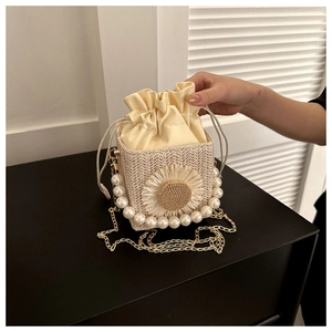Detail of straw box bag with sunflower decoration, pearl handle, and gold chain strap