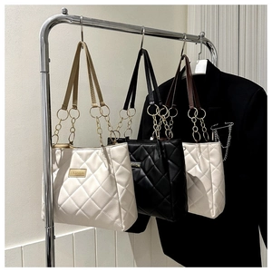 Close-up of quilted tote bag with gold chain handles and fashion metal plaque