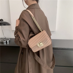 Elegante beige plissierte kleine quadratische Tasche mit goldener Kette am Modell
