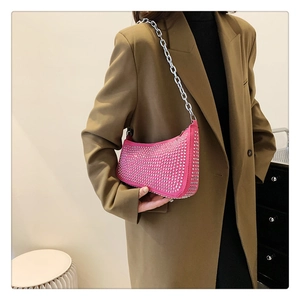 Hot pink rhinestone crescent shoulder bag with metallic chain strap worn over a brown blazer