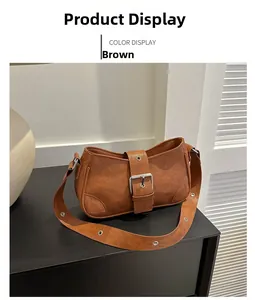 Detail view of brown matte leather shoulder bag with metallic buckle in home setting