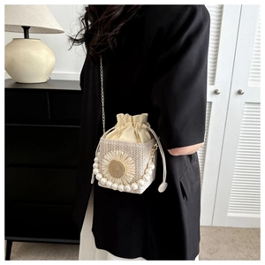 Detail view of woven straw bucket bag featuring 3D sunflower and pearl handle strap