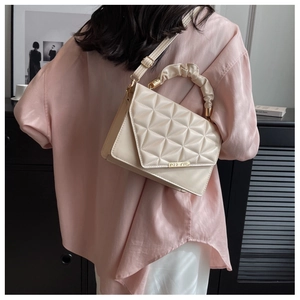 Détail du sac à rabat beige matelassé avec poignée froncée et garniture en métal doré